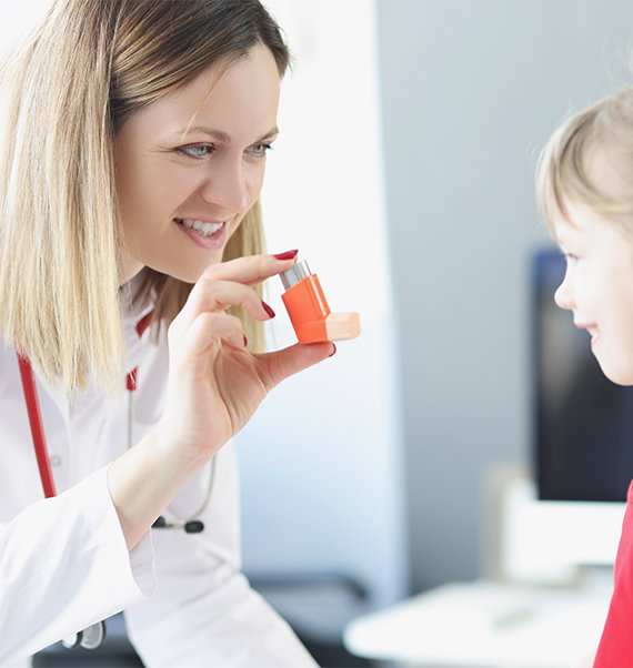 Pharmacist in respiratory counselling appointment with child, showing child how to use an asthma inhaler.